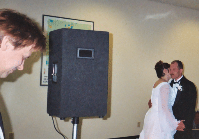 Photograph of Newlywed's first dance as DJ Looks on.